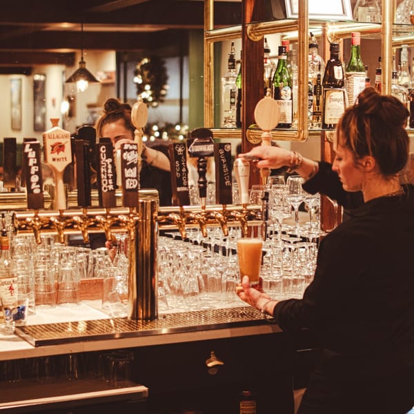 A bartender at Rodney's at 436 Main pours a beer from a tap at a well-stocked bar.